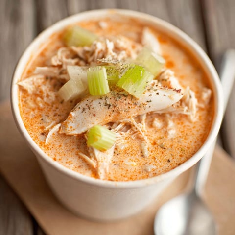 A bowl of soup with chicken and vegetables.