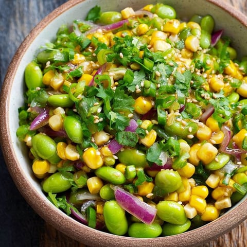 A bowl of food with corn, beans, and cilantro.