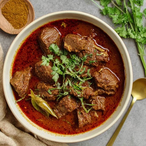 A bowl of Indian beef curry with meat and vegetables.