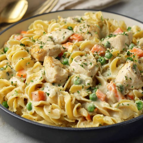A plate of pasta with chicken and peas.