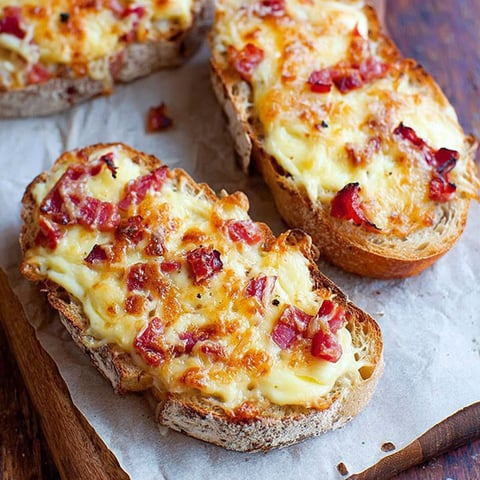 Two slices of bread with cheese and ham on top.