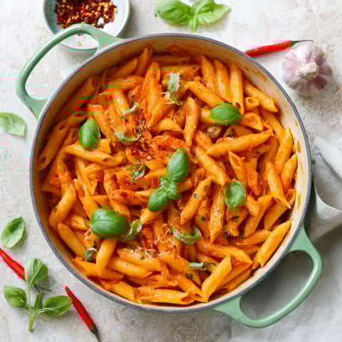 A pot of pasta with vegetables and spices.