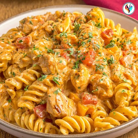 A plate of pasta with chicken and tomatoes.