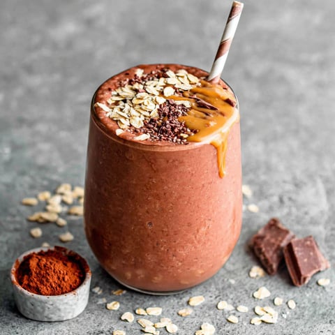 A glass of oatmeal smoothie with a straw.