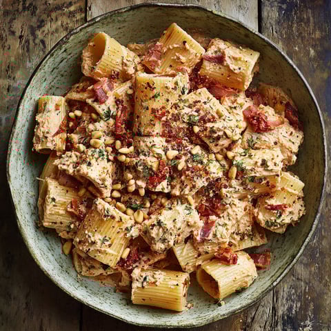 A bowl of pasta with sun-dried tomato ricotta pesto.