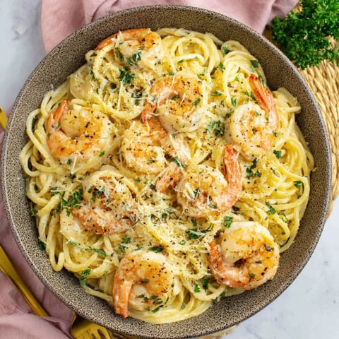 A bowl of spaghetti with shrimp and cheese.